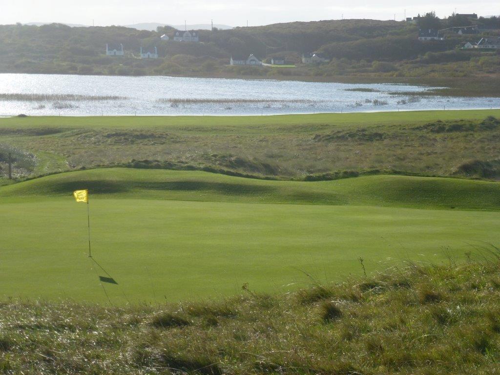 Golfgrün mit Markierungsfahne und Meeresblick auf dem  Narin und Portnoo Golfplatz in Irland
