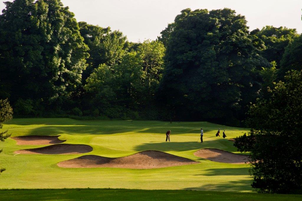 Golfgrün mit Bunker und Golfspieler auf dem Belvoir Golfplatz in der Nähe von Belfast, Nordirland