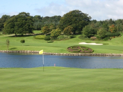 Golfgrün mit Markierungsfahne und Fluss auf dem Slieve Russel Golfplatz in der Nähe von Dublin, Irland