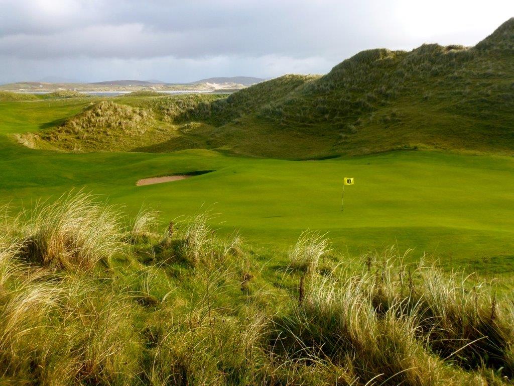 Golfgrün mit Markierungsfahne und Meeresblick auf dem  Narin und Portnoo Golfplatz in Irland